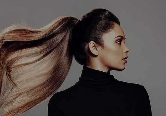Woman with sleek ponytail and black turtleneck, looking to the side.